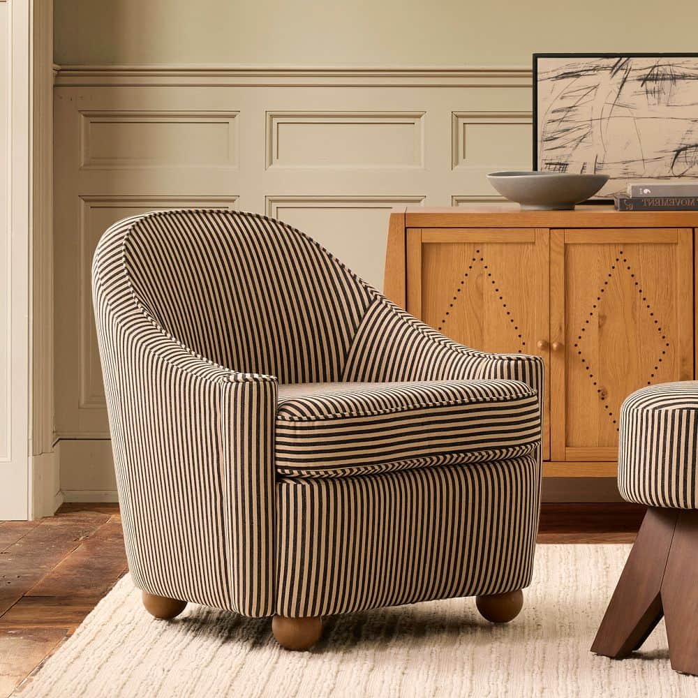 A compact armchair upholstered in fabric with a black and tan vertical stripe pattern. It features a… — 3D model