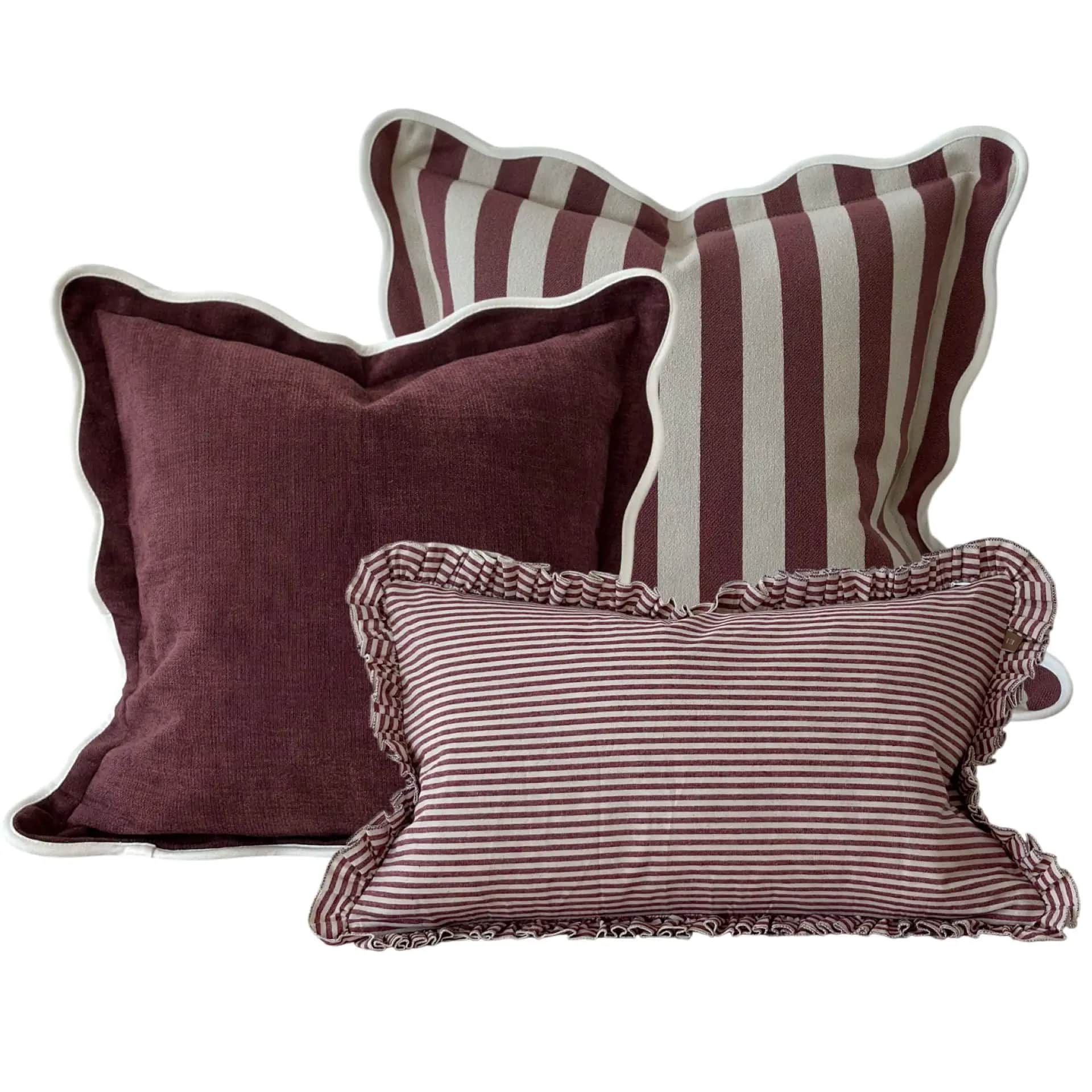 A set of three decorative pillows. One pillow is a solid dark red color with a scalloped edge trimme… — 3D model