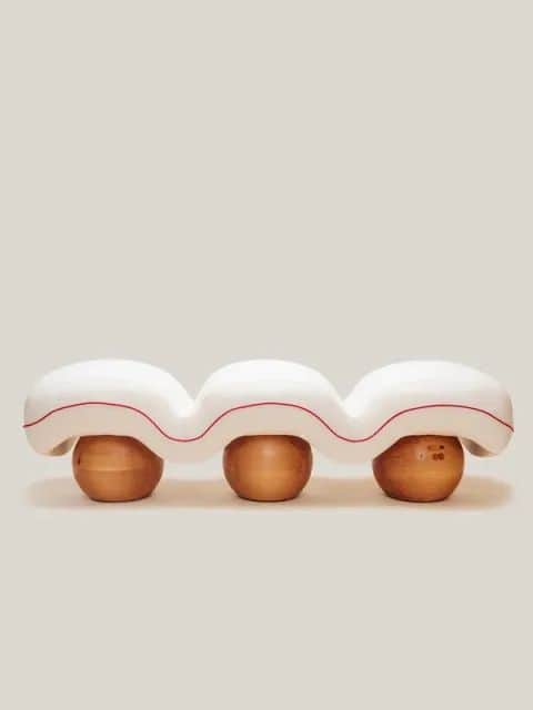 A contemporary bench with a wavy, bulbous white upholstered seat. The seat is supported by three sph… — 3D model