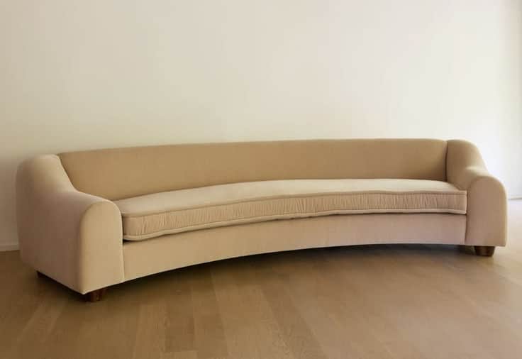 A modern curved sofa featuring a beige upholstered fabric, low profile, and simple block feet. The d… — 3D model