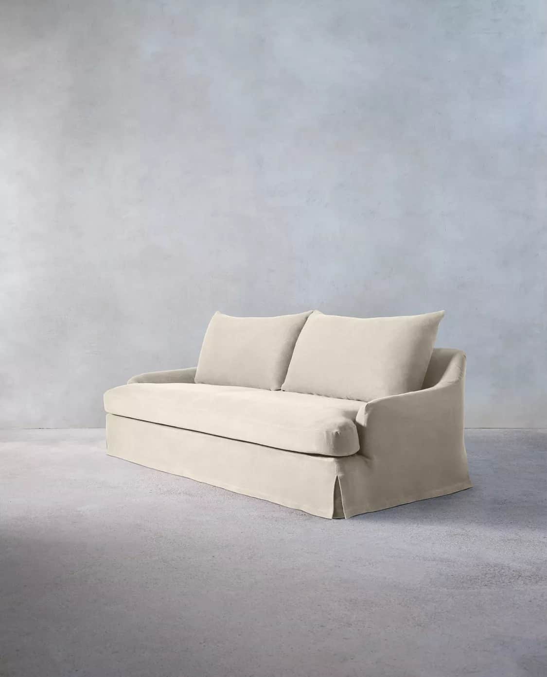 A light-colored, slipcovered two-seater loveseat with a casual aesthetic, featuring a skirted base a… — 3D model