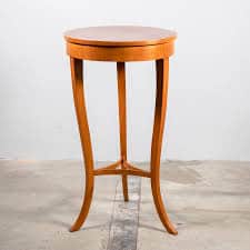 A tall, slender pedestal table with a circular top and three curved legs that meet at a central supp… — 3D model