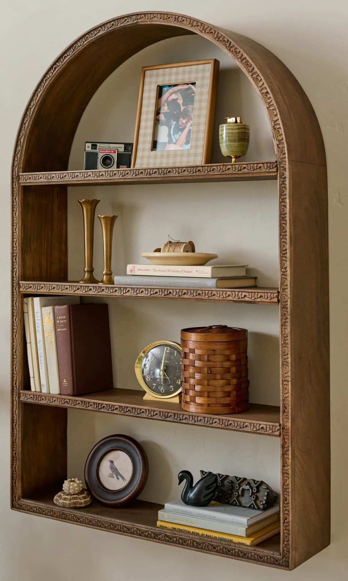 A wooden bookshelf with an arched top and three shelves. The frame and edges of the shelves are ador… — 3D model