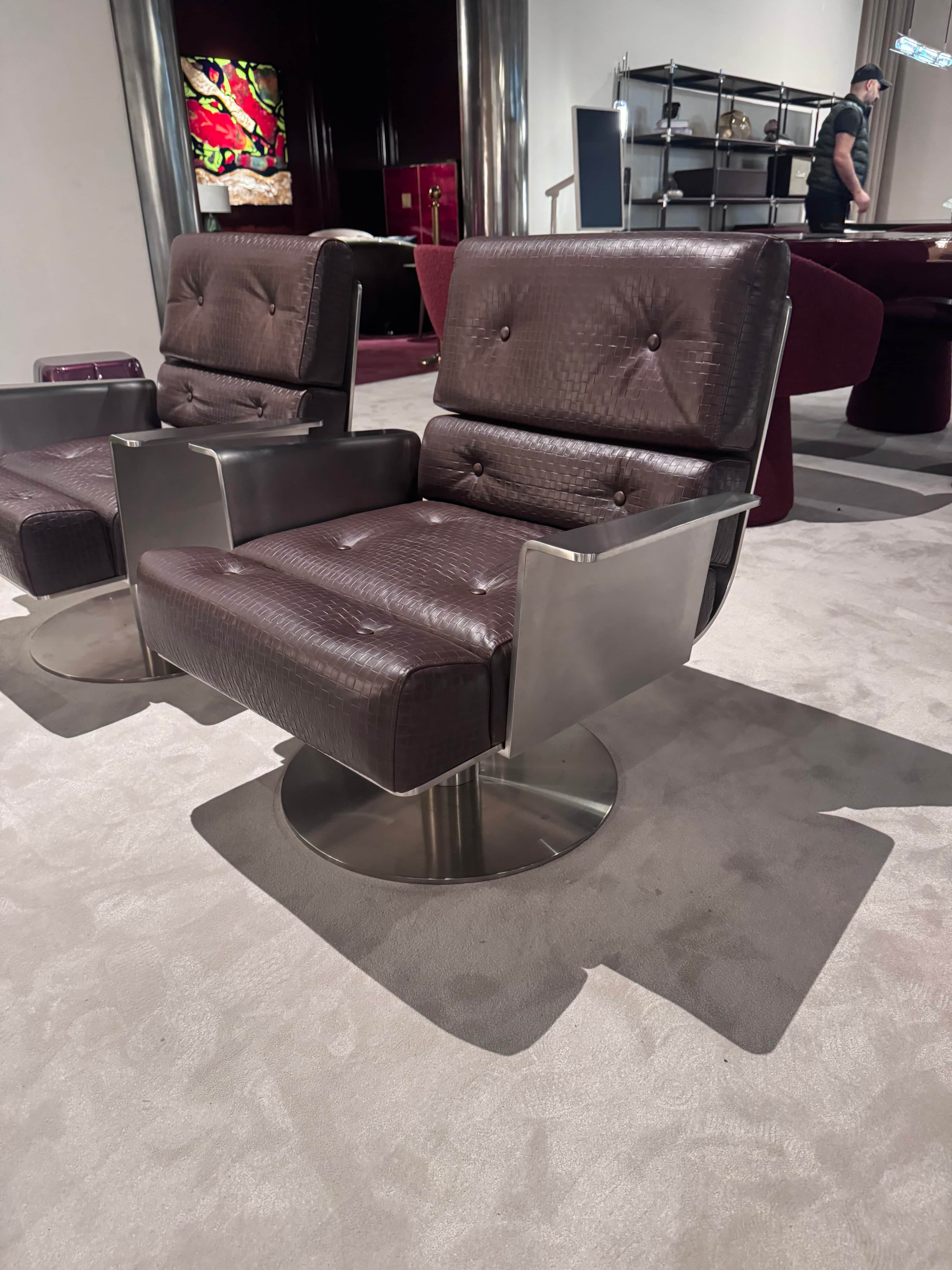 A modern armchair featuring a swiveling base. The seat and backrest are upholstered in dark brown le… — free OBJ 3D model