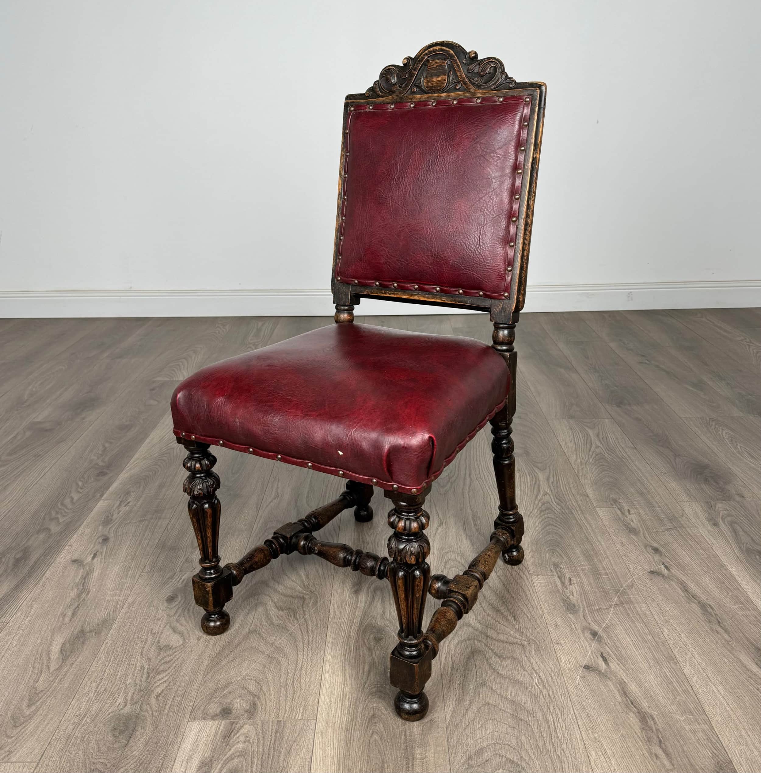 An ornate, traditional side chair featuring a dark carved wood frame and burgundy leather upholstery… — 3D model