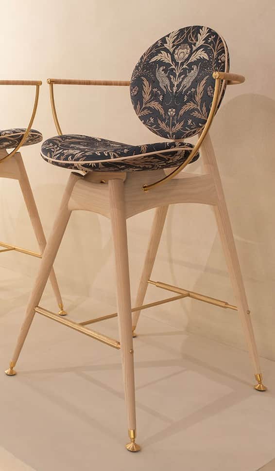 A tall, contemporary bar stool featuring a light-toned wooden frame, brass accents, and distinctive… — 3D model