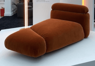 A plush, contemporary chaise lounge upholstered in a warm, rust-colored velvet-like fabric, featurin… — 3D model