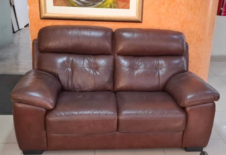 A contemporary two-seater loveseat upholstered in rich brown leather. It features plump, padded seat… — free GLTF 3D model