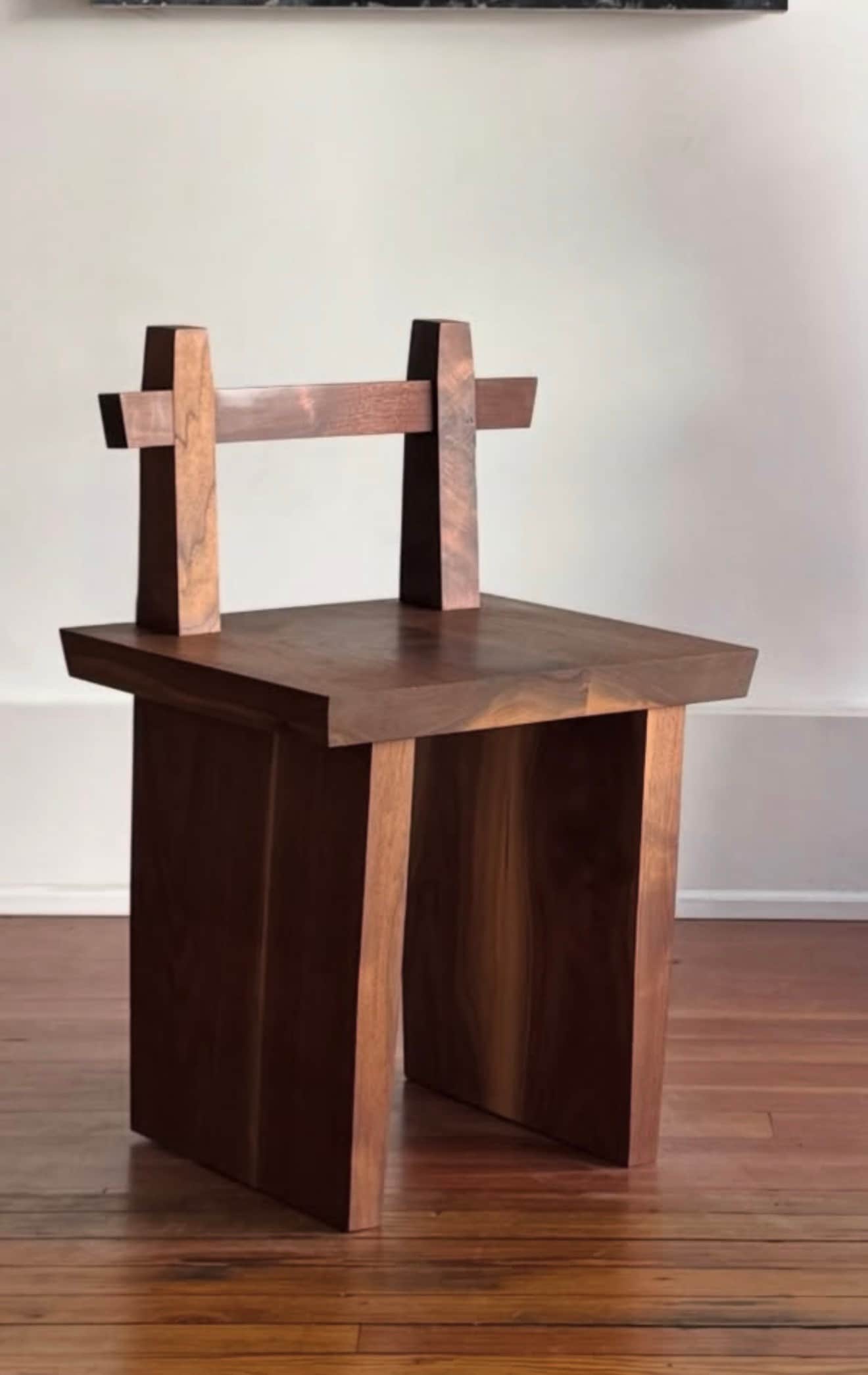 A minimalist low chair constructed from dark, solid wood, featuring a thick, rectangular seat and a… — 3D model