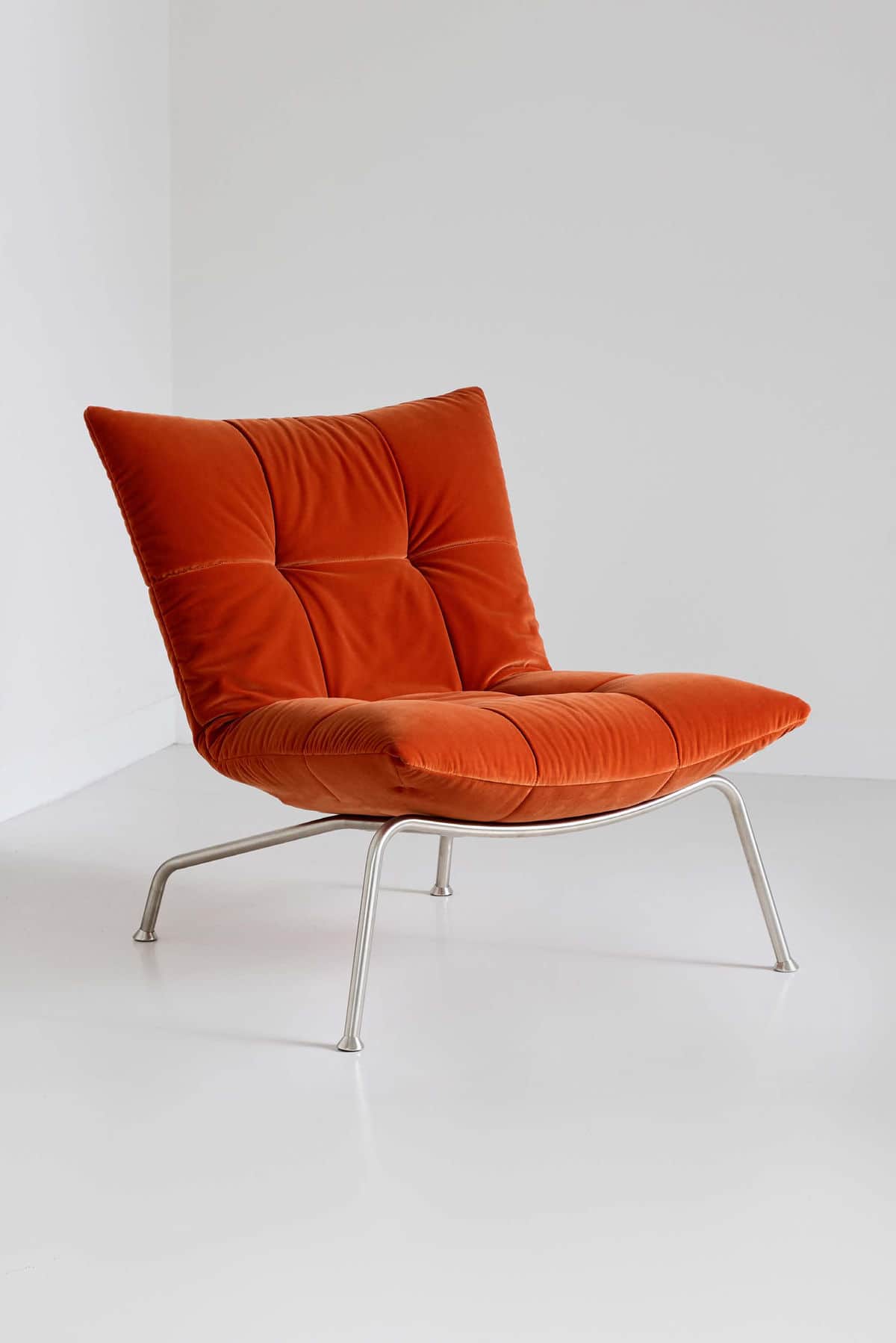 A modern lounge chair featuring plush, tufted burnt orange velvet upholstery and a sleek, minimalist… — free OBJ 3D model