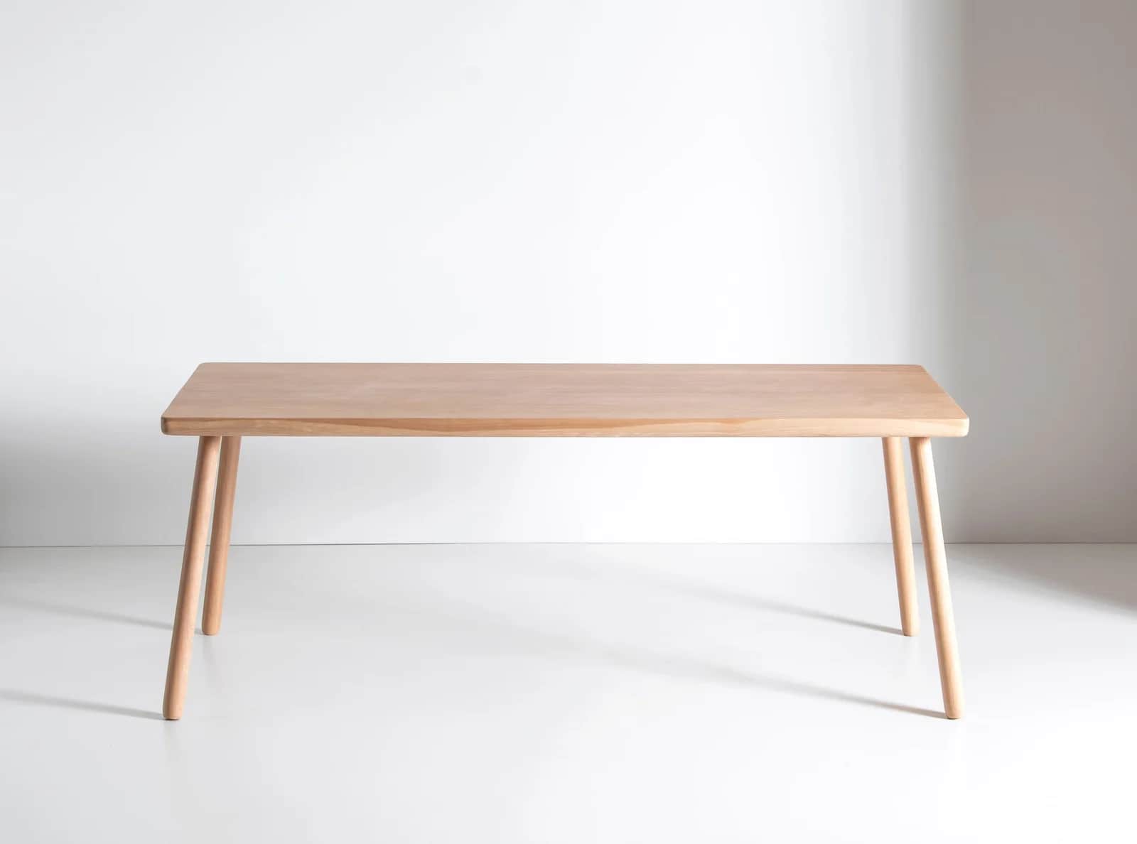 A light-toned wooden rectangular table featuring a smooth top with softly rounded corners and four t… — 3D model