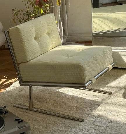 A modern armless lounge chair featuring a polished metal frame and thick, tufted cushions upholstere… — 3D model