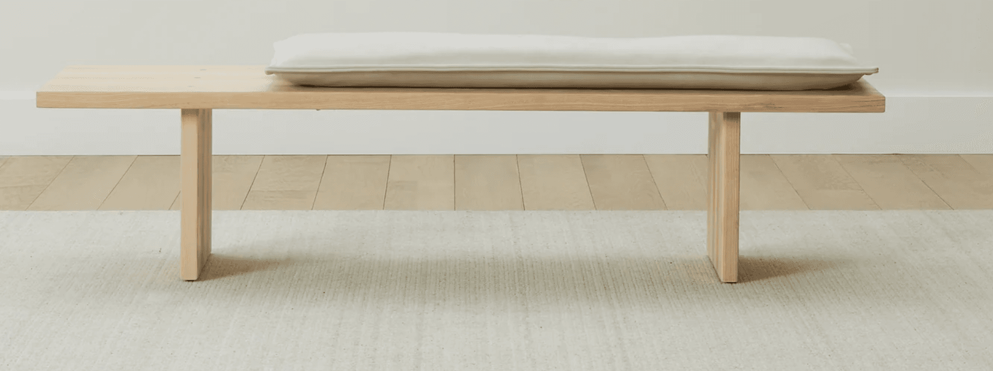 A minimalist wooden bench featuring a light-colored, rectangular cushion. The bench is constructed f… — 3D model