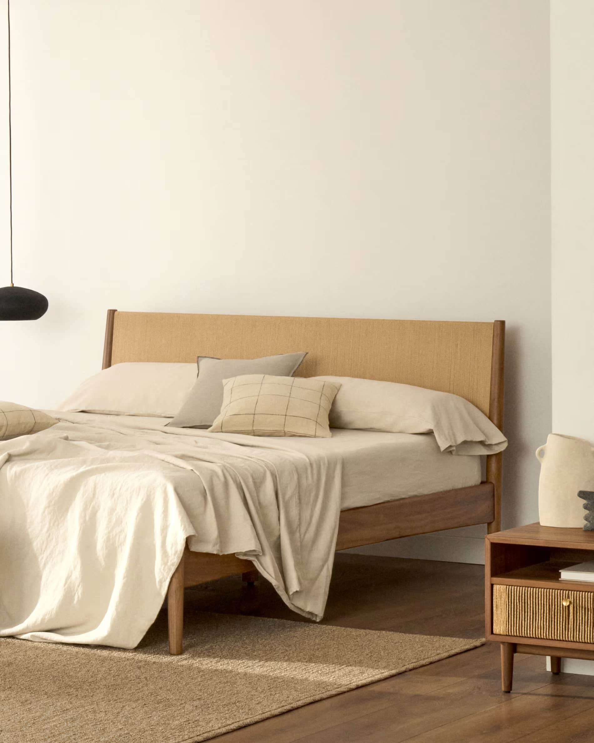 A modern platform bed featuring a clean-lined wooden frame and a headboard with a woven cane or ratt… — 3D model