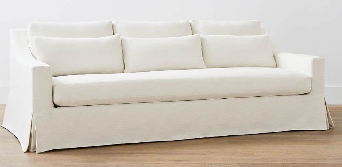 A three-seater sofa with a skirted base and loose back cushions. The sofa has track arms and is upho… — free GLTF 3D model