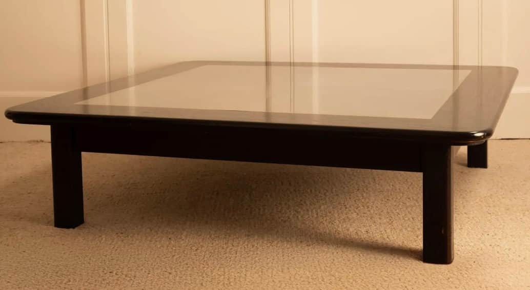 A low-profile square coffee table with a dark-finished wooden frame and a recessed, lighter-colored… — 3D model