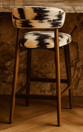 A modern bar stool featuring a sturdy wooden frame and distinctive cowhide-patterned upholstery on b… — 3D model