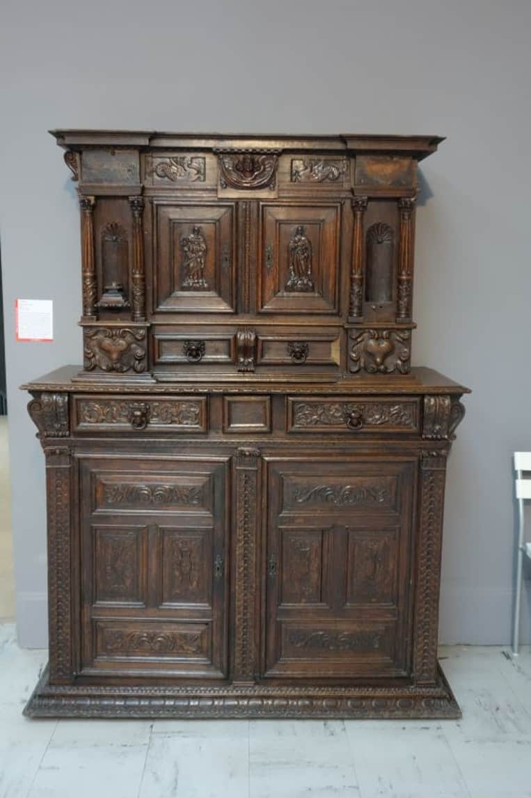 A tall, dark wooden cabinet with intricate carvings. The cabinet features a tiered design with multi… — 3D model