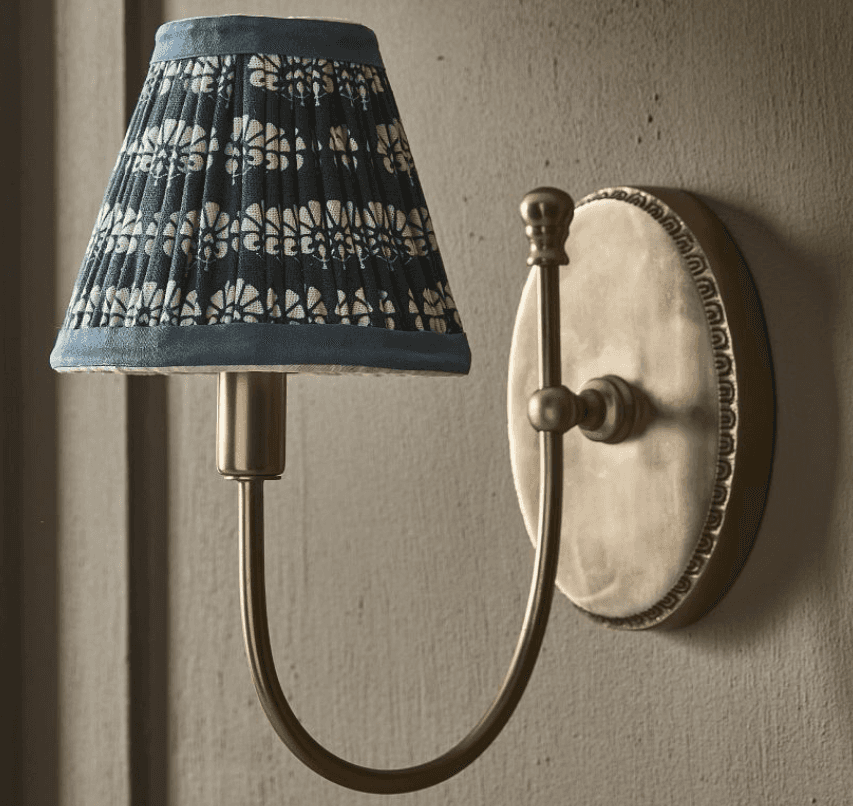 A wall-mounted lamp featuring a pleated lampshade with a decorative pattern and a curved arm support… — 3D model