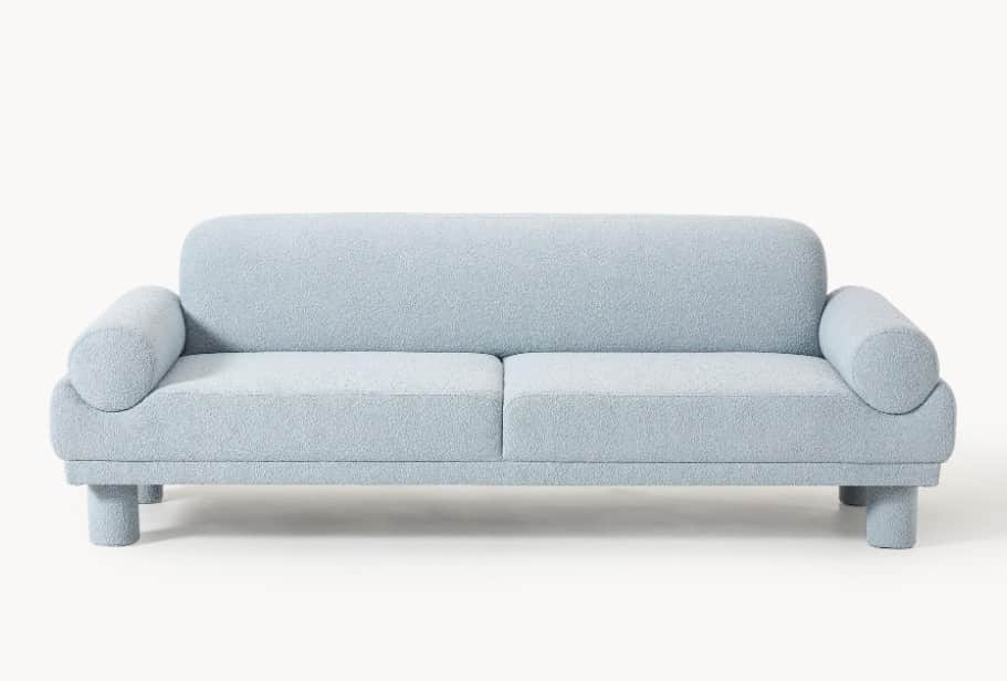 A light blue, plush-textured sofa with a rounded backrest and armrests. It features two seat cushion… — free GLTF 3D model