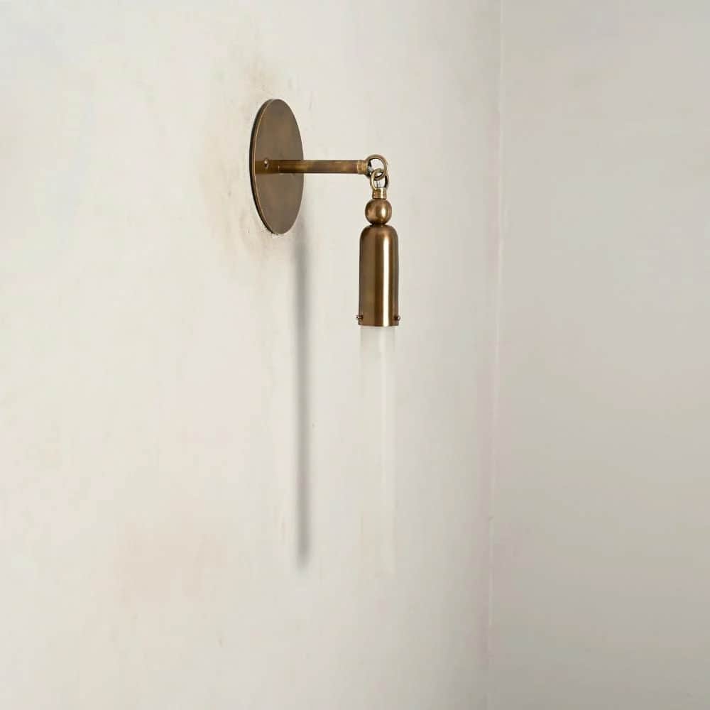 A modern wall sconce featuring a circular brass wall plate, an articulating arm, and a cylindrical b… — 3D model