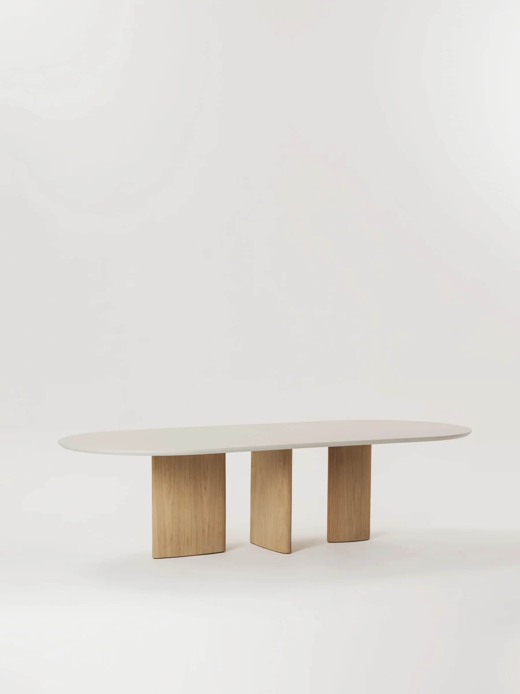 An oval-shaped dining table featuring a smooth, light grey tabletop and three substantial, solid woo… — free OBJ 3D model