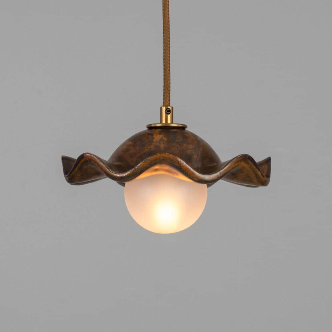 A pendant light featuring a distinctive wavy, shell-like metal shade with a mottled, patinated bronz… — free GLB 3D model