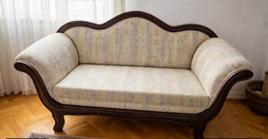 A traditional style chaise lounge featuring a dark, carved wooden frame and light-colored upholstere… — 3D model