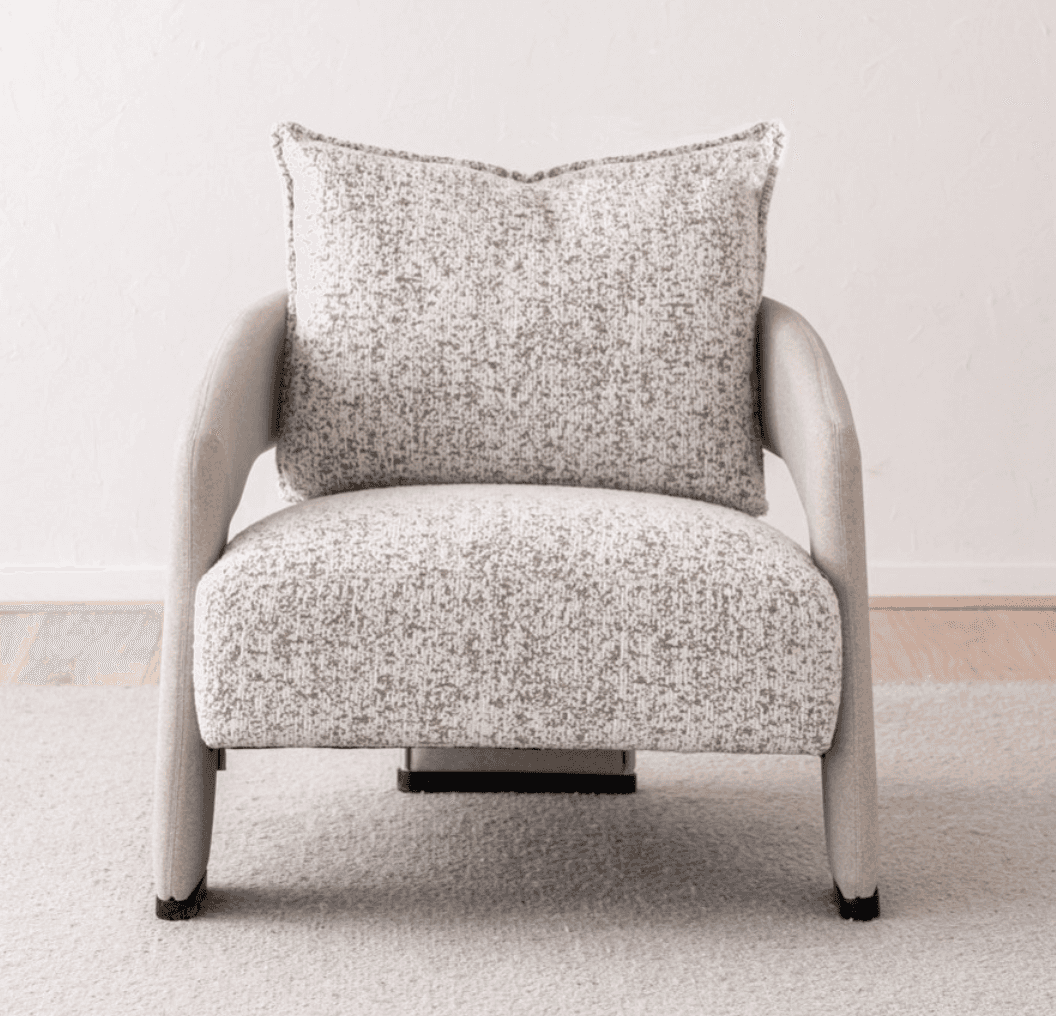 A contemporary upholstered armchair featuring a rounded silhouette and a neutral-toned, speckled fab… — 3D model