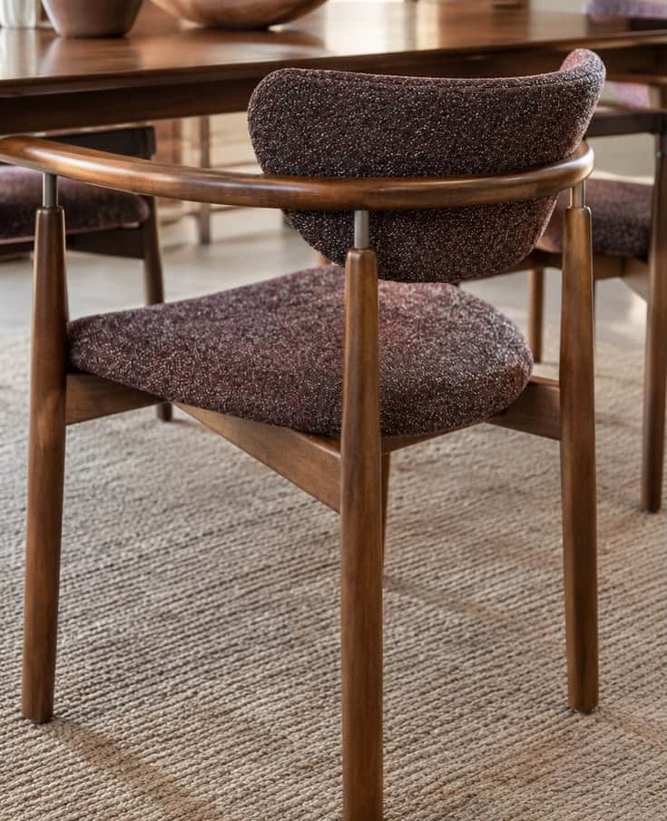 A contemporary dining armchair featuring a dark brown wooden frame, integrated armrests, and speckle… — 3D model
