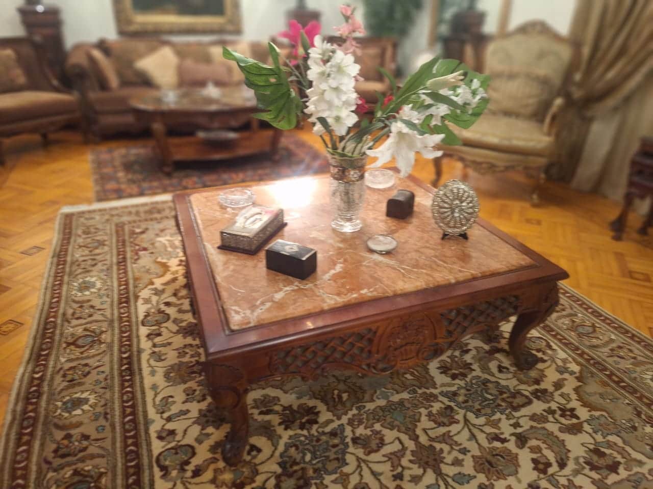 A square, traditional coffee table featuring a polished brown marble top with white and lighter brow… — 3D model