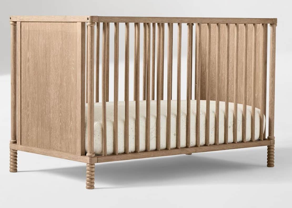 A wooden crib with slatted sides and a solid headboard/footboard. The crib has a mattress inside wit… — 3D model