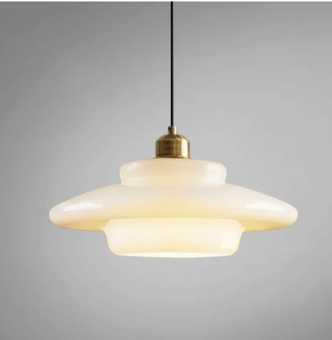 A contemporary pendant light featuring a layered opal glass shade suspended by a black cord with bra… — 3D model