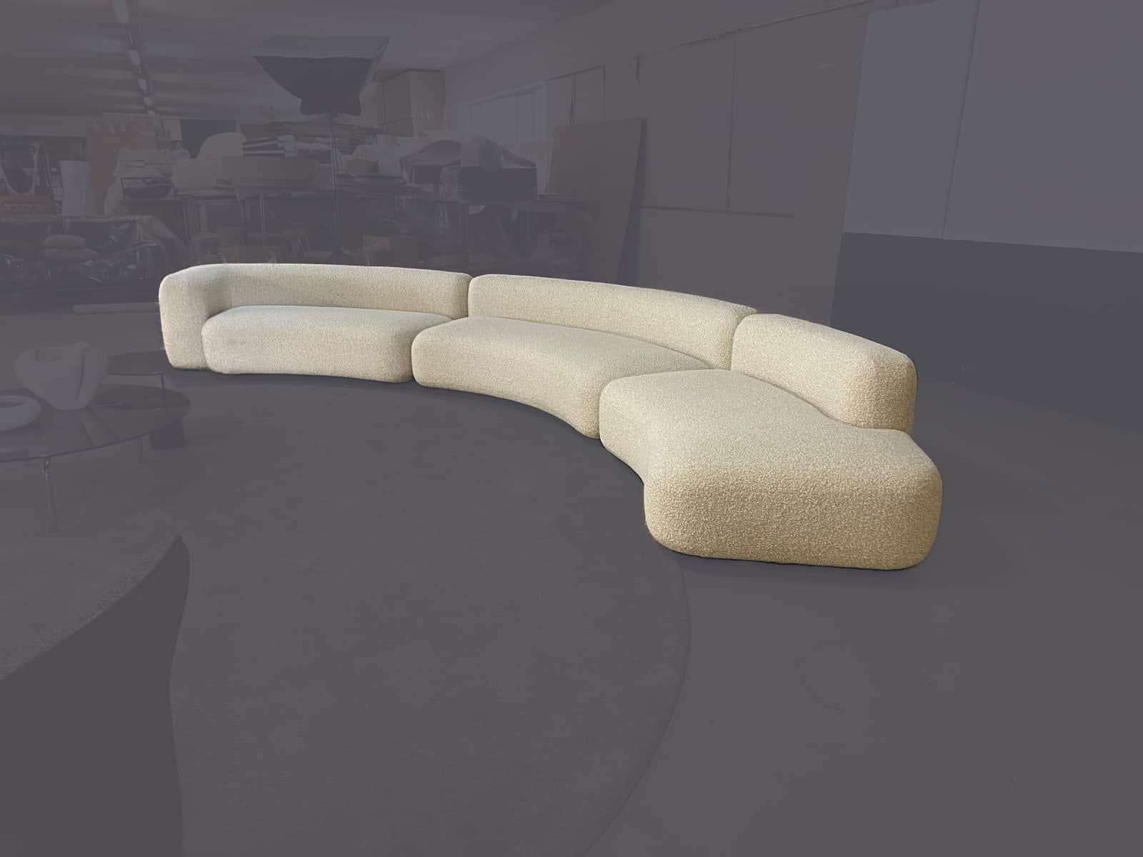A large, modular sectional sofa with a distinct curved or serpentine silhouette, upholstered in a te… — 3D model