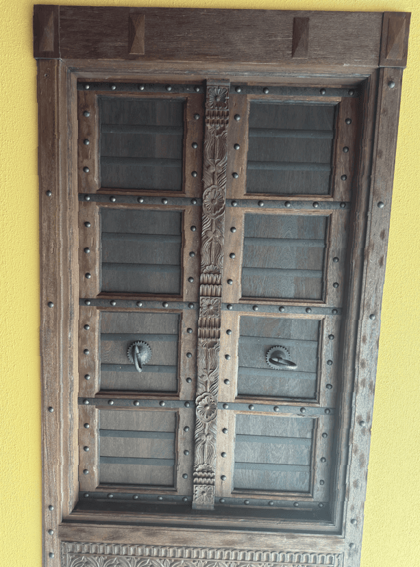 A vintage wooden door with intricate carvings and metallic accents. It features multiple rectangular… — 3D model