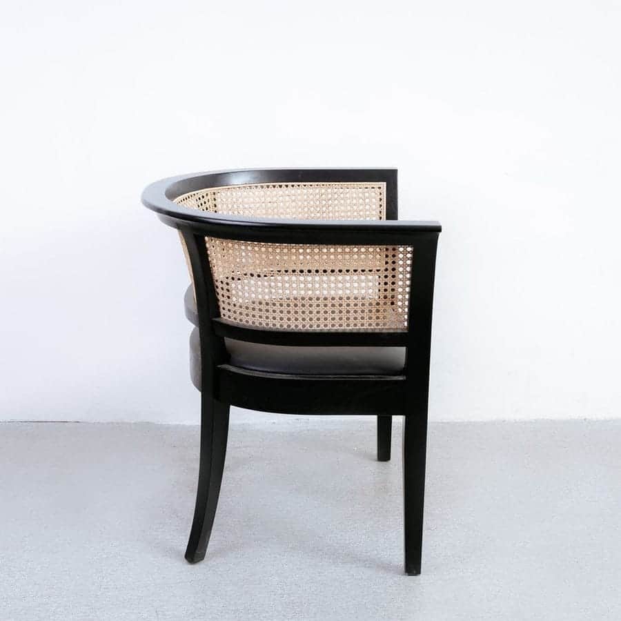 An elegant armchair featuring a black wooden frame with a curved backrest and natural cane webbing.… — 3D model
