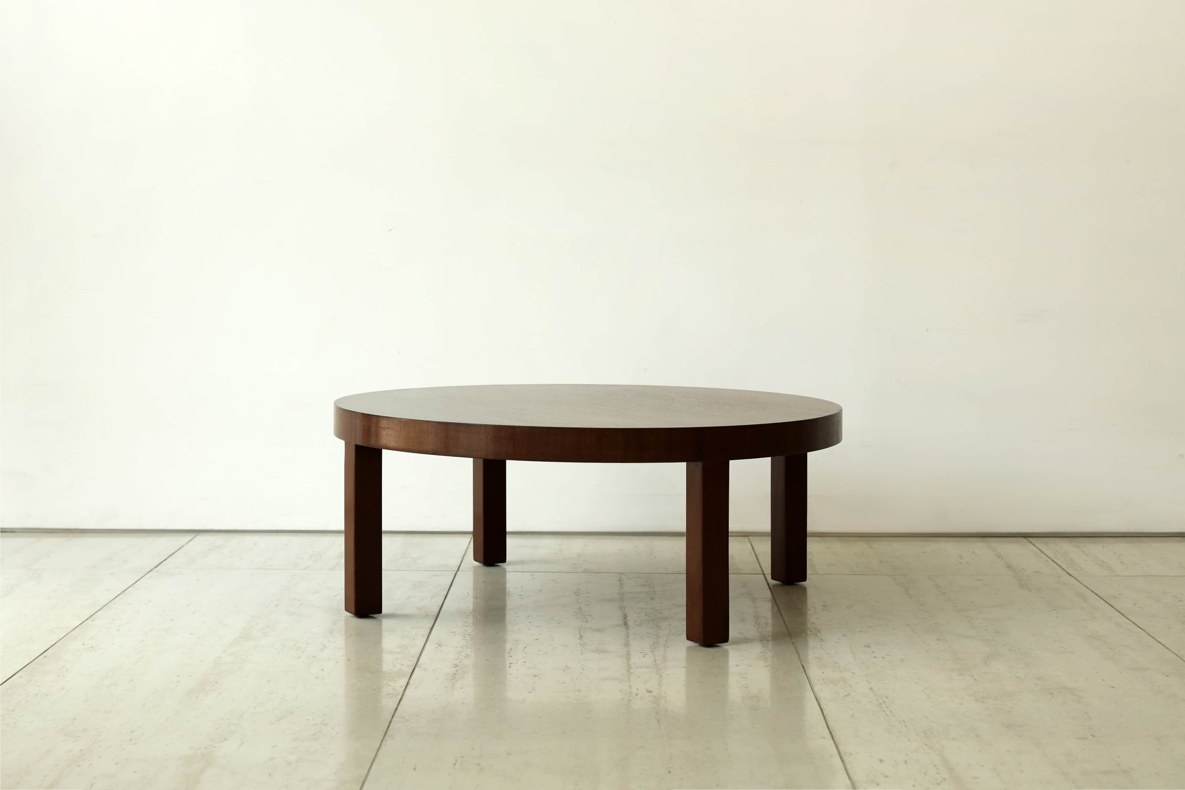 A minimalist round coffee table crafted from dark wood, featuring a thick circular top supported by… — 3D model