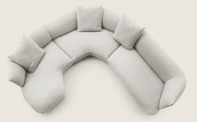 A sectional sofa with a curved, modular design, upholstered in a light-colored, textured fabric. The… — 3D model