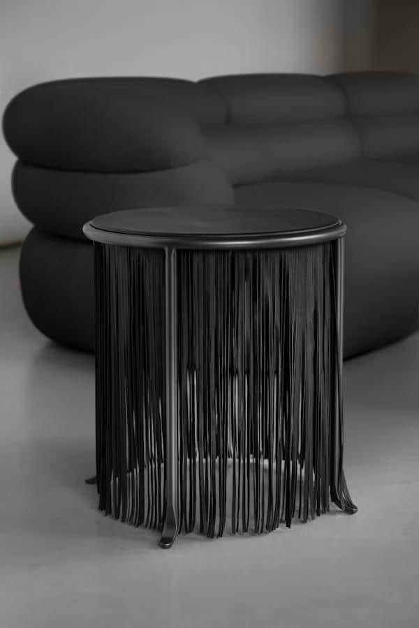 A black round table featuring a unique fringe-like design for its base, supported by three subtle fe… — 3D model
