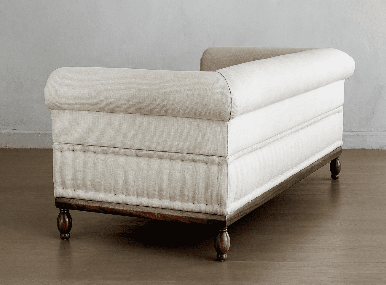 A cream-colored upholstered daybed with a rolled armrest and a tufted lower section. The daybed is s… — 3D model