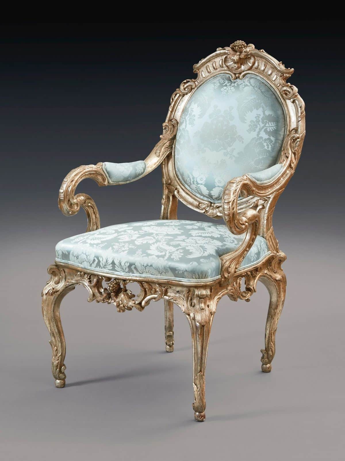 A highly ornate, antique-style armchair featuring a carved, distressed giltwood or silver-leafed fra… — 3D model