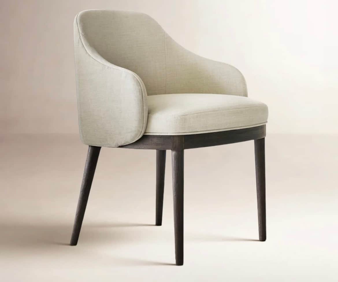An upholstered armchair with a curved barrel back and armrests, set on four dark, tapered wooden leg… — 3D model
