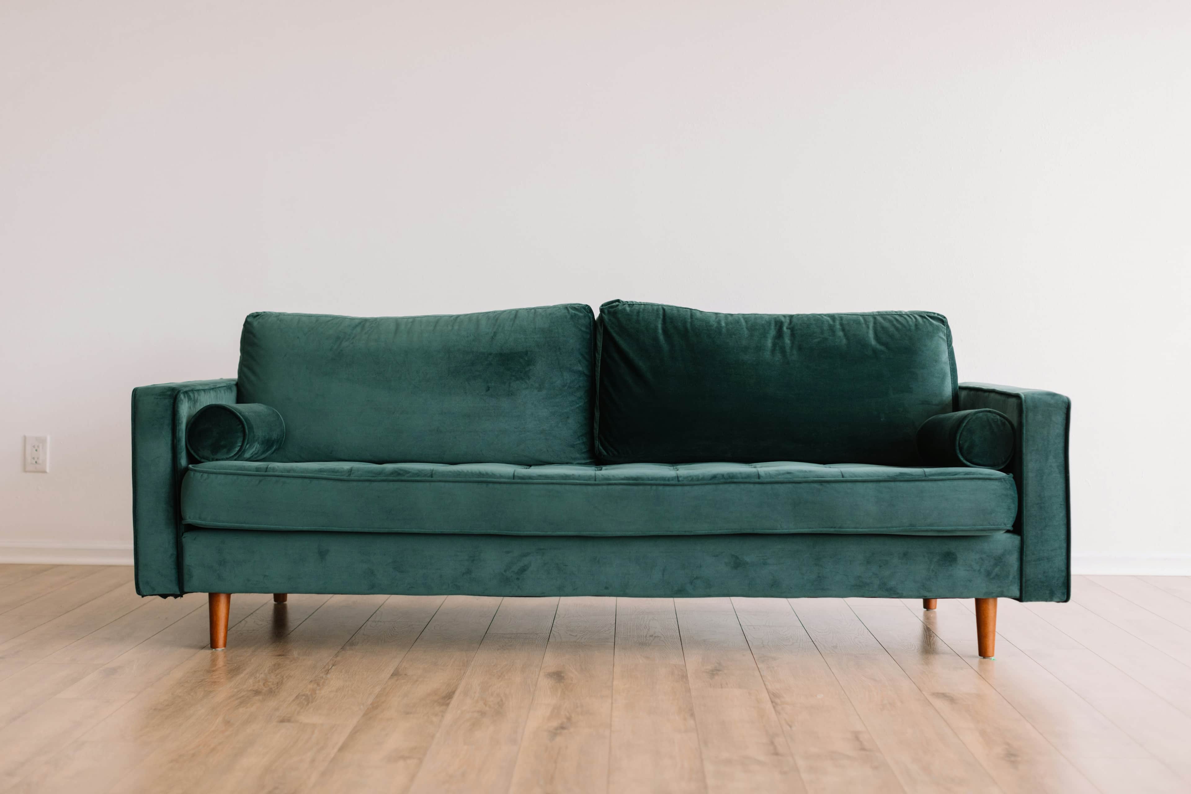 A modern three-seater sofa upholstered in a rich emerald green velvet fabric. It features a button-t… — 3D model