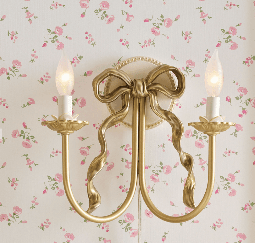 A decorative wall sconce designed to resemble a candle holder with a bow motif. It features two cand… — 3D model