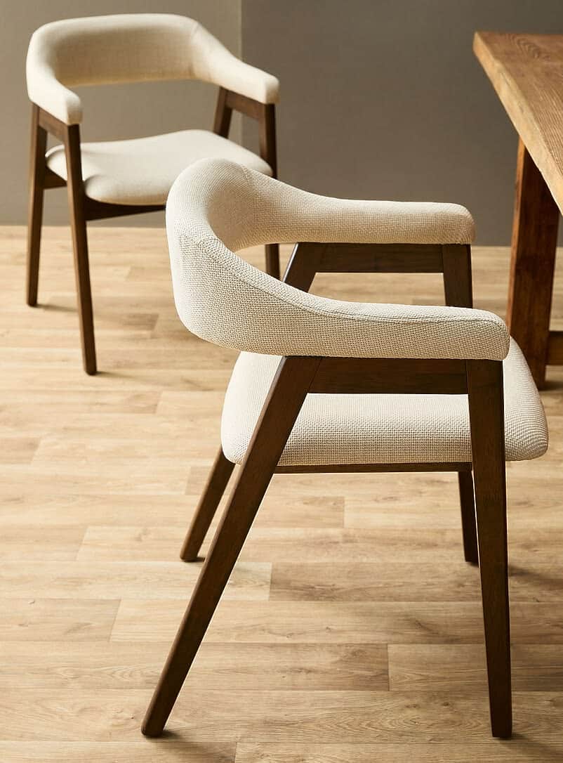 A modern armchair featuring a dark wood frame and cream-colored textured upholstery. The chair has a… — 3D model
