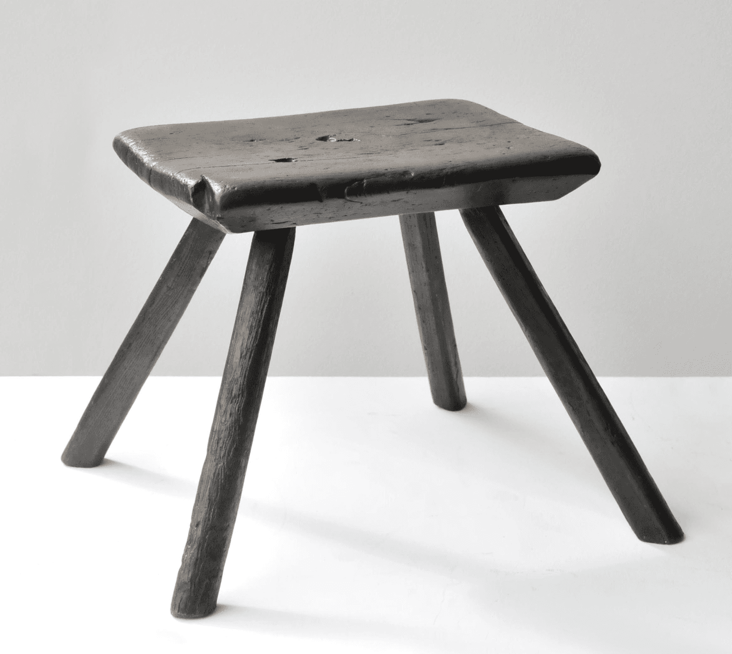 A rustic wooden stool with a square seat and three legs. The seat is flat with rounded edges and sho… — 3D model