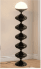 A tall, modern floor lamp featuring a sculptural base composed of six stacked, bulbous, glossy black… — 3D model