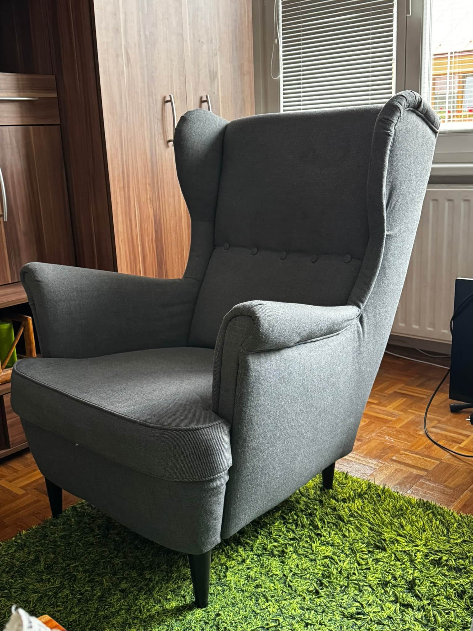 A contemporary wingback armchair upholstered in a textured grey fabric. The chair features a tall, s… — 3D model