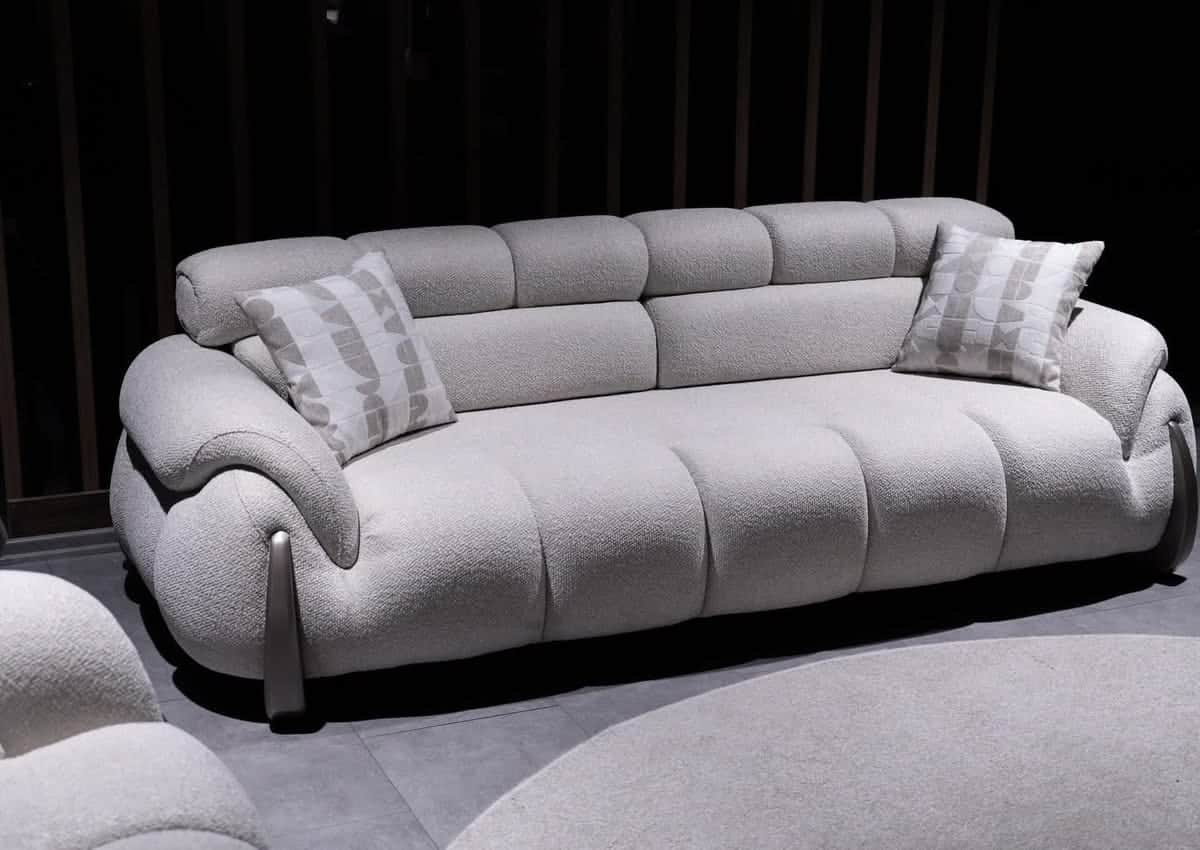 A modern, large, light gray upholstered sofa featuring distinct rounded, segmented cushions and a ch… — 3D model