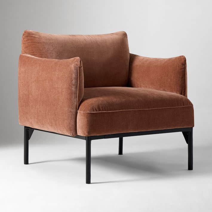 A modern armchair featuring a plush, upholstered seat, back, and arms, supported by a slender black… — 3D model